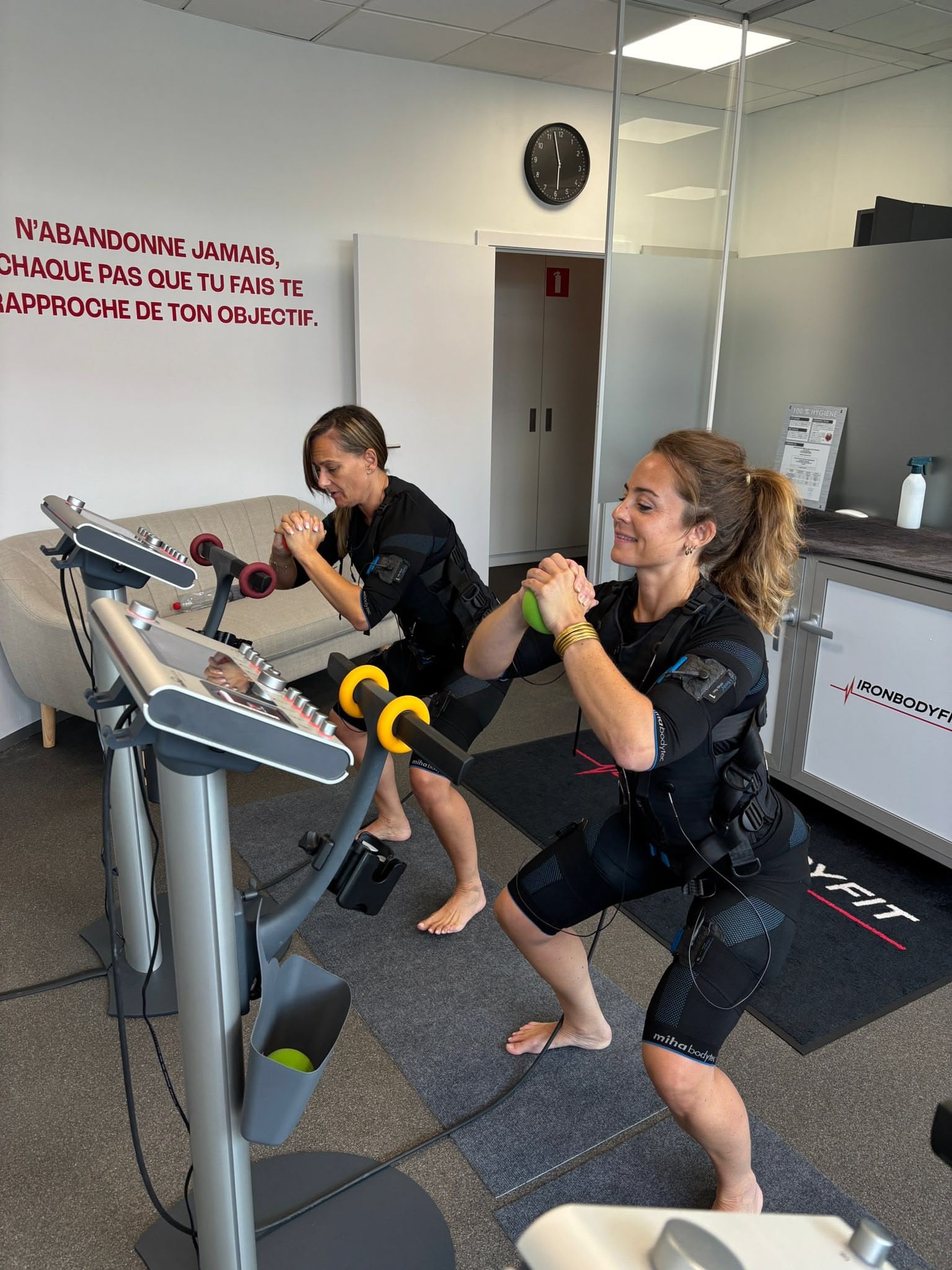 Deux participantes en tenue EMS faisant des exercices au studio